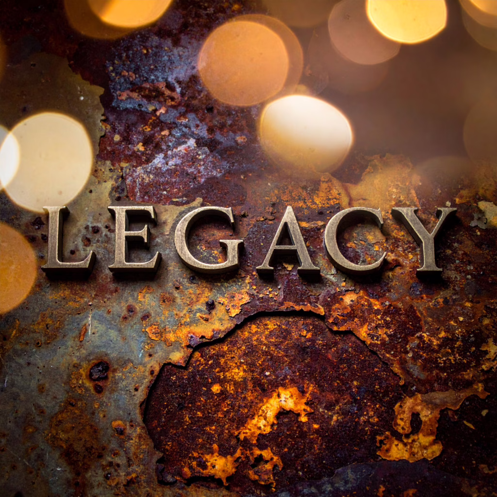 Close-up of metallic 'LEGACY' lettering embedded in textured rusted wall, bokeh lights in background.